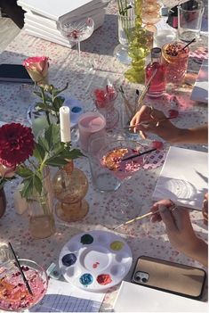 people sitting at a table with flowers and paints