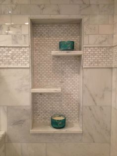 a bathroom with white marble walls and shelves filled with green glass bowls on top of each shelf