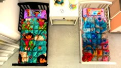 an overhead view of two baby cribs with colorful blankets and toys in them