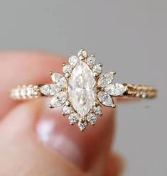 a woman's hand holding an engagement ring with a white diamond in the center