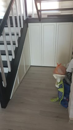 there is a baby sitting on the floor in front of a stair case next to some toys