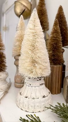 small white christmas trees sitting on top of a table next to other ornaments and decorations