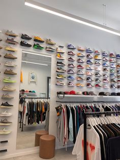 a room filled with lots of shoes and t - shirts hanging on the wall next to each other