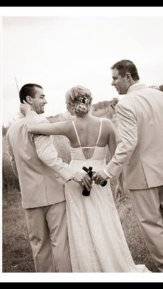 two men and a woman standing next to each other in front of a field with grass