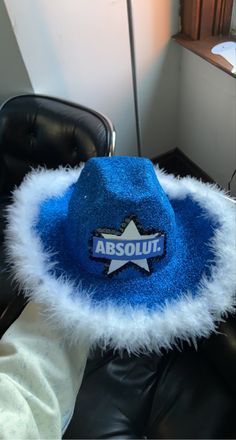 a blue and white hat with the word absolut on it sitting on a black leather chair