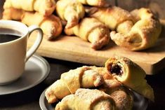 some pastries are on a plate next to a cup of coffee and saucer