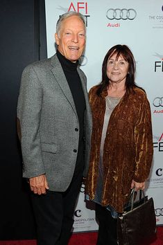 an older man and woman standing next to each other on the red carpet at afi awards