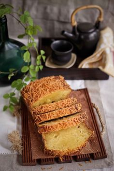 sliced cake sitting on top of a wooden tray next to a green potted plant