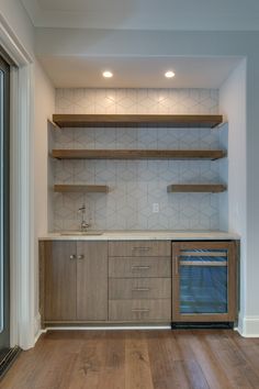 an empty kitchen with wood flooring and open shelving