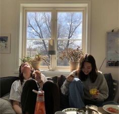 two women sitting on a couch with drinks in their hands