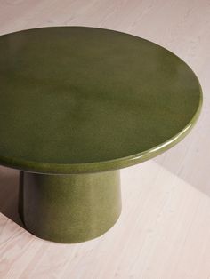 a green table sitting on top of a wooden floor