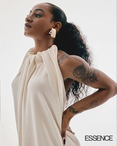 a woman with tattoos on her arms and back, wearing a white dress from essence