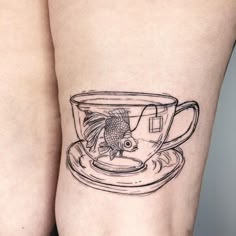 a fish in a coffee cup tattoo on the left side of the right leg,