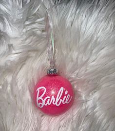 a pink bauble ornament with the word barbie written on it in white lettering