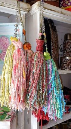 several different colored bags hanging from hooks on a shelf in a room with other items