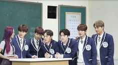 group of young men standing in front of a desk