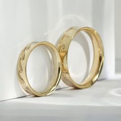 two gold wedding rings sitting next to each other