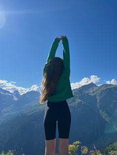 a woman standing on top of a mountain with her arms in the air