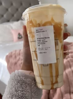 a person holding up a cup with caramel drizzle on it