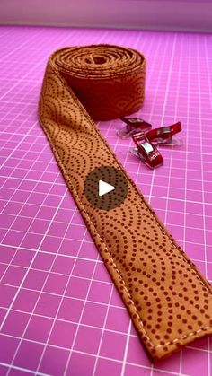 a brown tie sitting on top of a pink counter next to a roll of tape