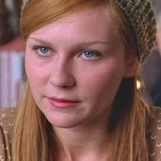 a woman with blue eyes wearing a knitted headband and looking at the camera