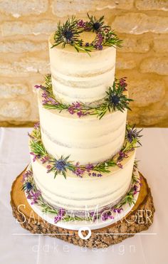 a three tiered white cake with purple flowers on it