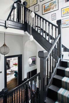 a staircase with pictures on the wall above and below it, leading up to a living room