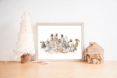 a christmas tree and some figurines in front of a white wall with a painting on it