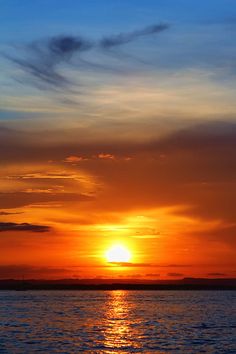 the sun is setting over the ocean with clouds in the sky and on the water