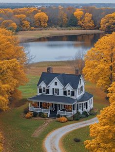 an aerial view of a large white house surrounded by trees with yellow leaves on it