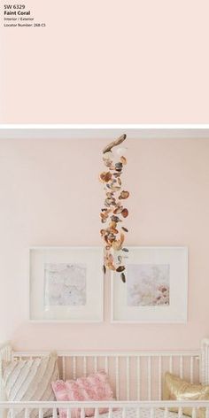 a baby's crib with pink walls and pictures on the wall above it