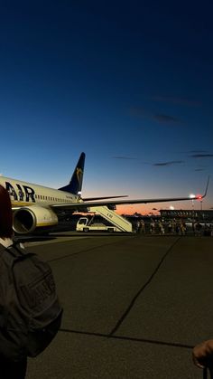 an airplane that is sitting on the tarmac at night with people standing around it