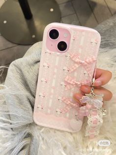 a person holding up a pink phone case with bows on the front and back cover