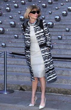 a woman standing in front of some steps wearing sunglasses and a black and white coat