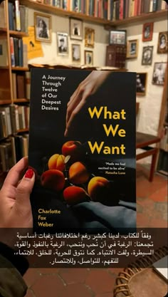 a person holding up a book in front of bookshelves