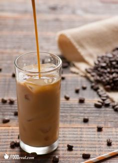 a glass filled with liquid next to coffee beans