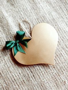 a heart shaped ornament with a green bow on it sitting on a table