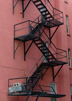 a fire escape on the side of a red brick building with stairs leading up to it