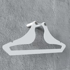 a pair of white clothes hangers on a gray wall with grey cement behind them