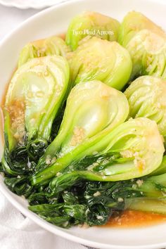 a white bowl filled with green vegetables covered in sauce