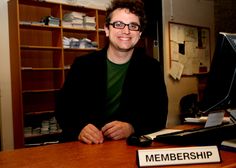 a man sitting at a desk with a sign that says, membership on it