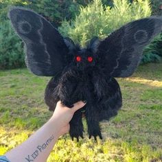 a hand holding a fake black bird with red eyes