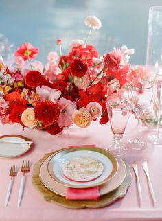 a table set with plates, silverware and flowers