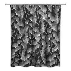 a black and white shower curtain with leafy leaves on it, in front of a dark background