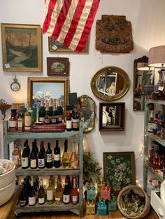 a room filled with lots of bottles of wine and framed pictures on the wall above it