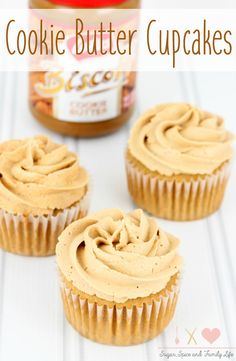 three cupcakes with peanut butter frosting in front of a jar of cookies