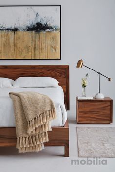 a bedroom with a bed, nightstand and painting on the wall