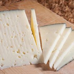 several wedges of cheese sitting on top of a wooden cutting board