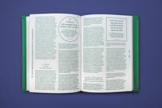 an open book with green pages and white lettering on the page is sitting on a blue surface