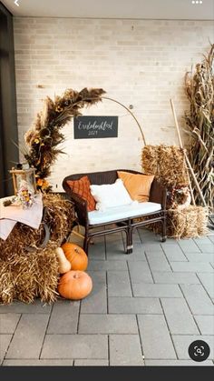 an outdoor area with hay, pumpkins and other decorations on the ground in front of a brick wall